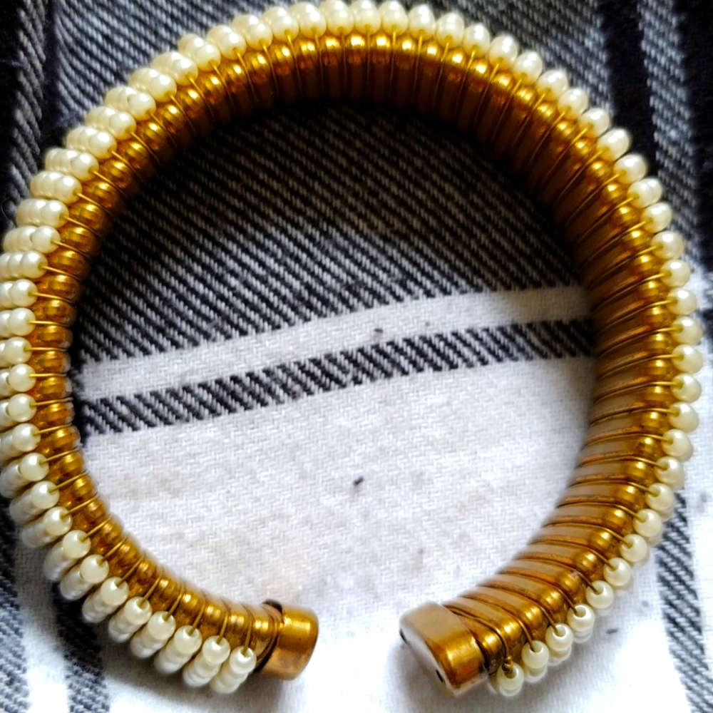 A gold bracelet with white beads.